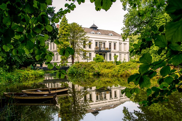 Achterkant van Kasteel de Berckt in Baarlo met sloepjes in het water
