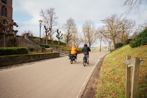 Twee fietsers fietsen langs het Rozenkerkje in Asselt in het najaar